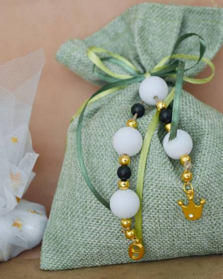 Μπομπονιέρα βάπτισης πουγκί στο χρώμα της ελιάς και δεμένο πάνω μπεγλέρι με κορώνα και το αρχικό του παιδιού